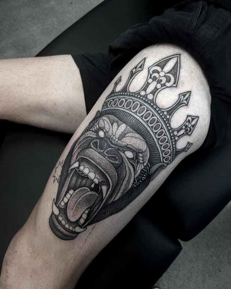 18. A tattoo of a gorilla wearing a crown on the thigh