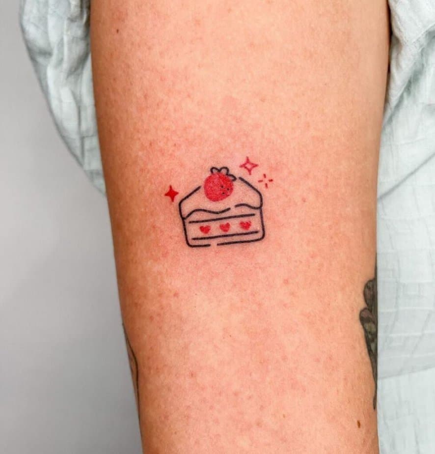 12. A cartoon cake tattoo on the upper arm
