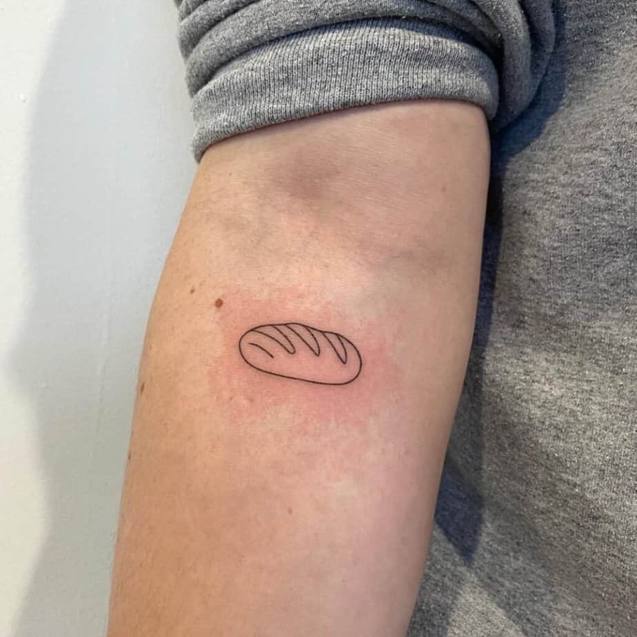 13. A linework loaf of bread tattoo on the forearm