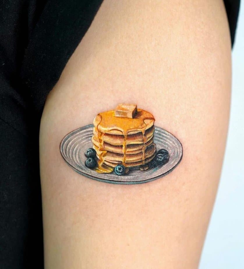 7. Tatuaggio di un pancake ai mirtilli sulla parte superiore del braccio