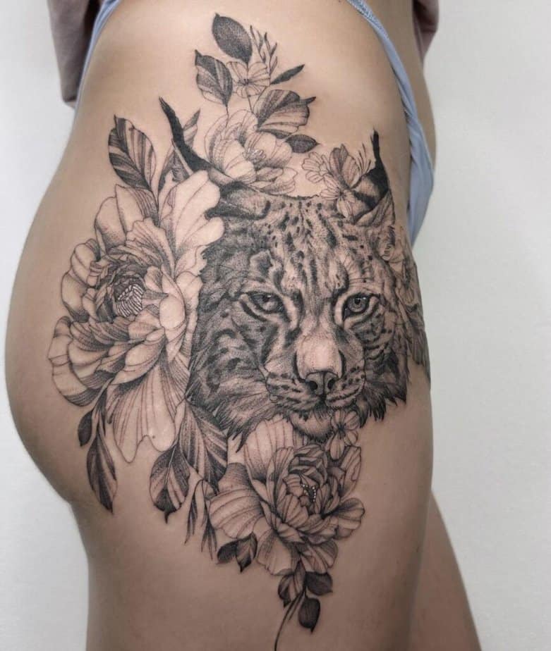 13. Un tatuaggio di una lince circondata da fiori sul fianco 