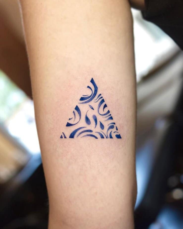 18. A blue ink triangle tattoo on the arm
