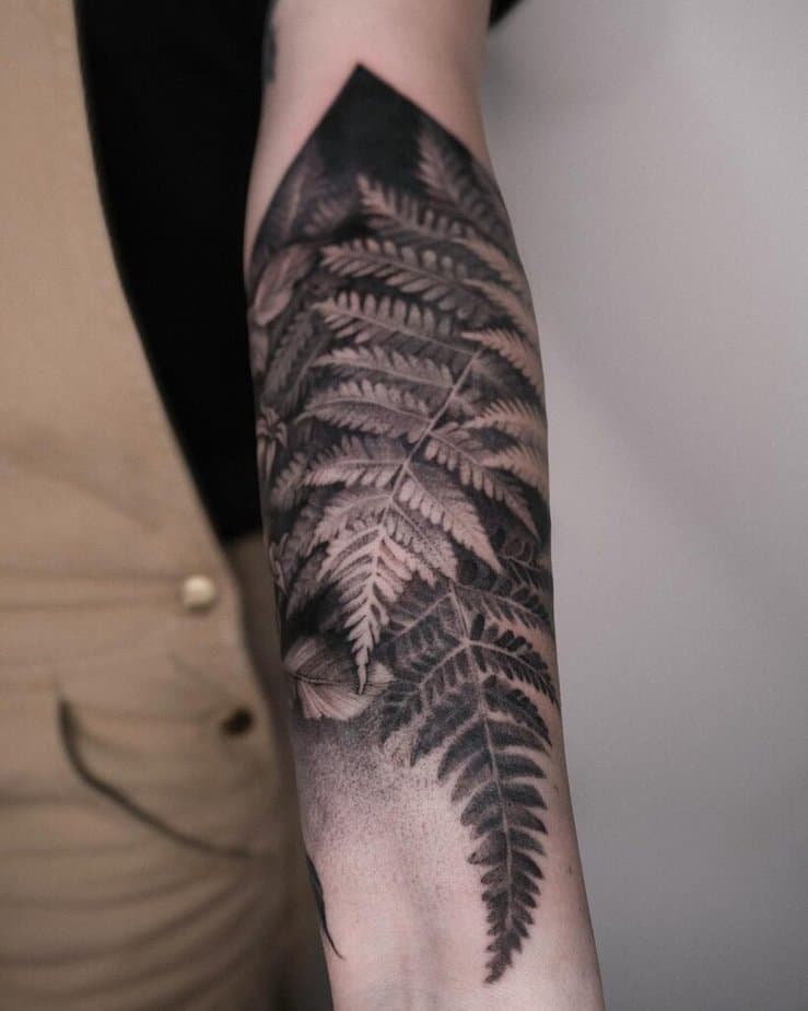 20. A blackwork fern tattoo on the forearm