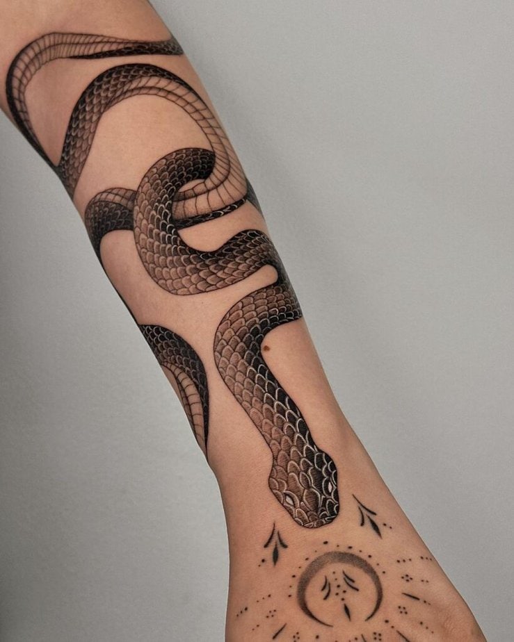 6. A forearm tattoo of a cobra with ornaments 