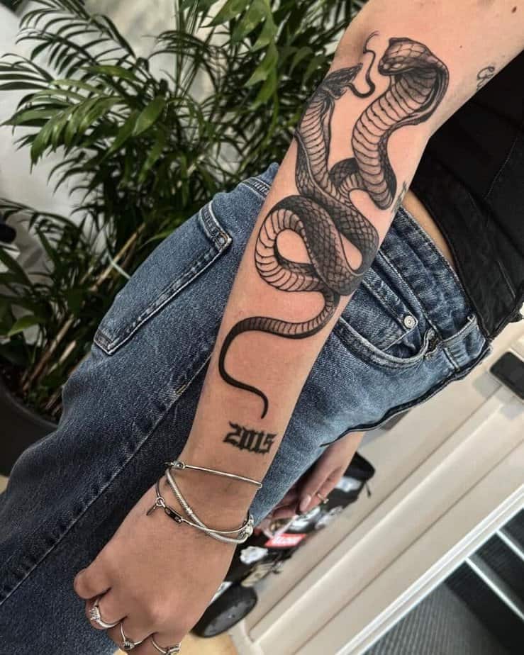 9. A two-headed cobra tattoo on the forearm