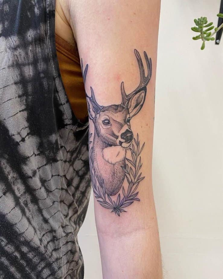 15. A deer tattoo with leaves on the upper arm
