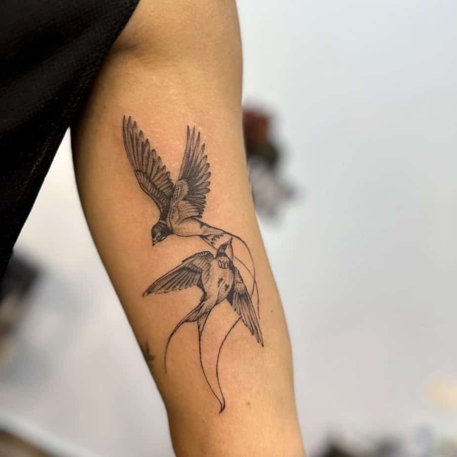 8. Un tatuaggio di due passeri realistici sulla parte superiore del braccio