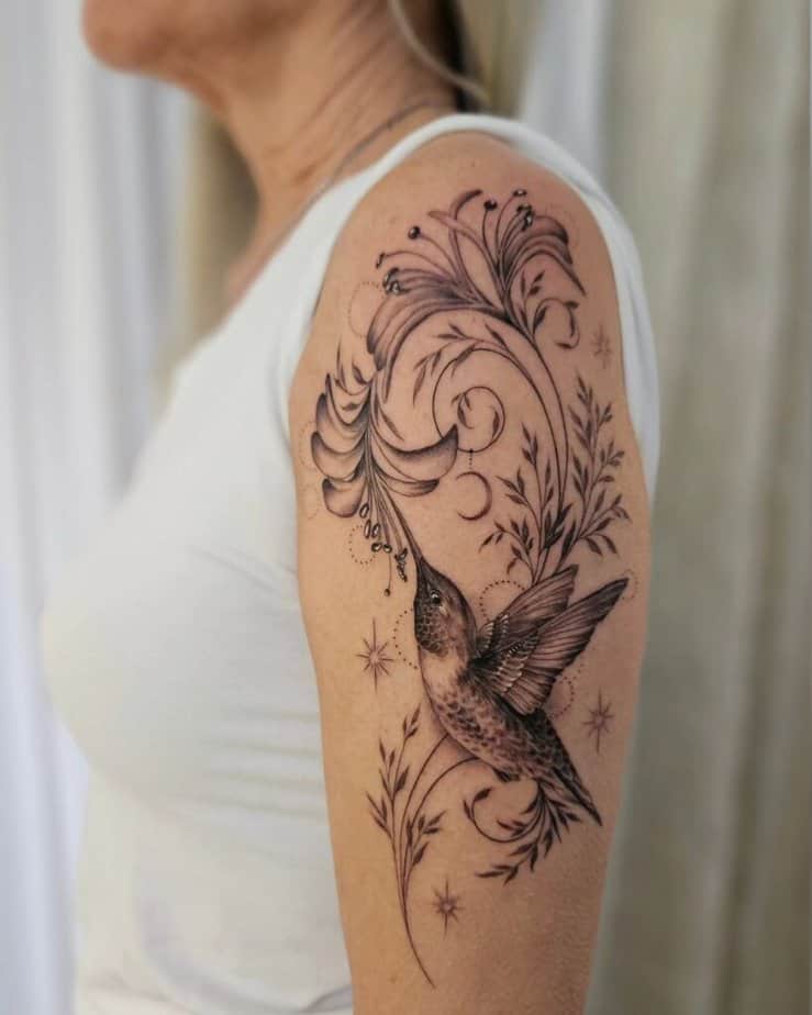 7. Hummingbird and flowers upper arm tattoo