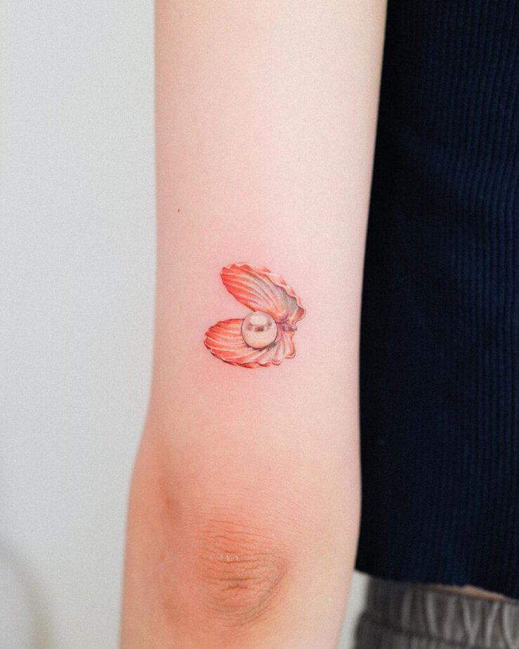 10. A tattoo of an orange seashell with a pearl
