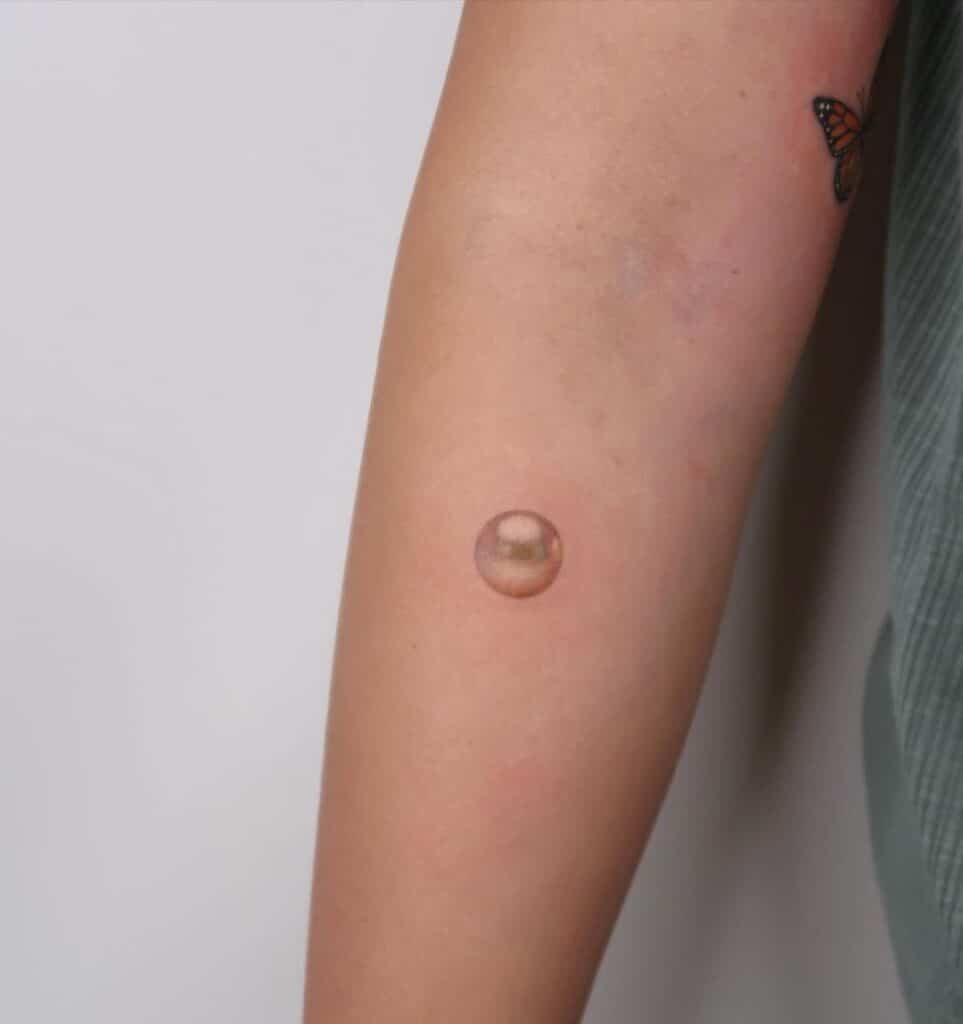 11. A realistic pearl tattoo on the forearm