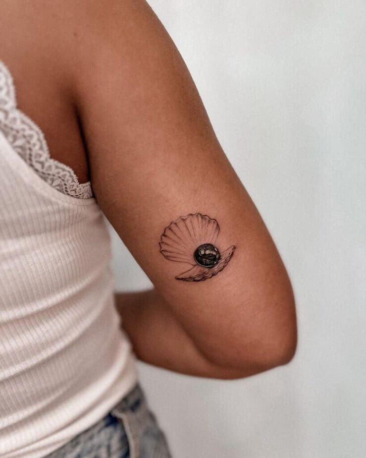 3. Tatuaggio di una conchiglia nera con perla sul retro del braccio