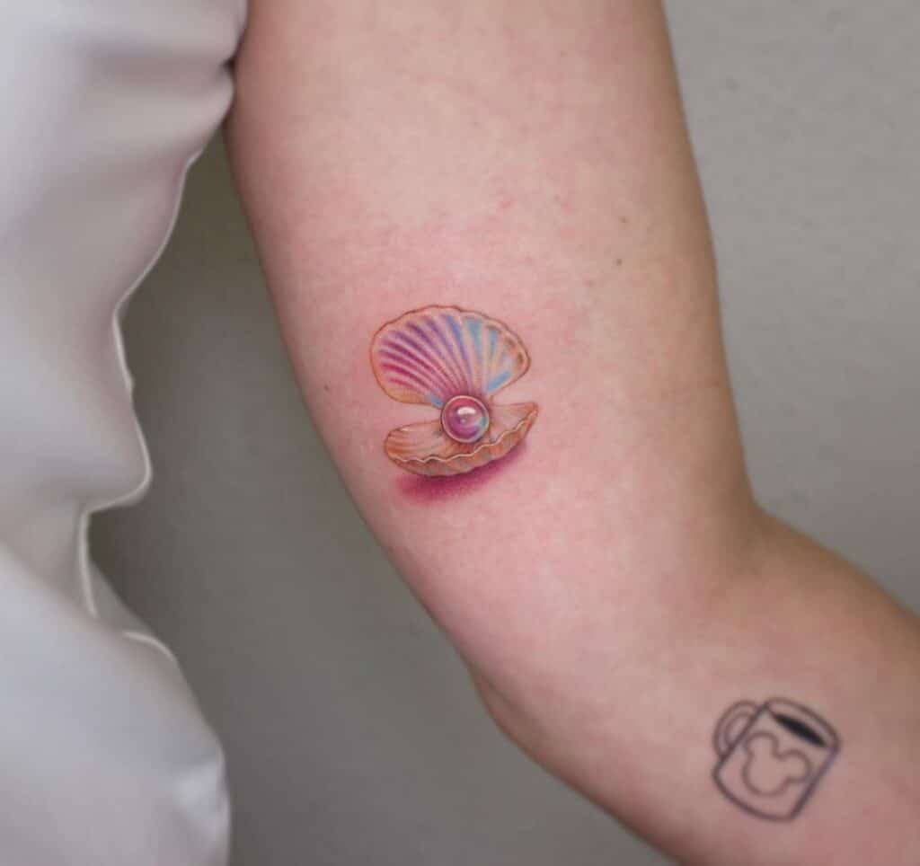 5. Un tatuaggio di una conchiglia perla iridescente sul bicipite