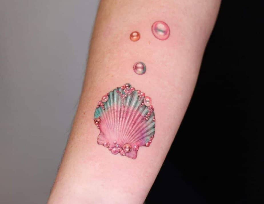 7. Tatuaggio di una conchiglia rosa ricoperta di perle iridescenti. 