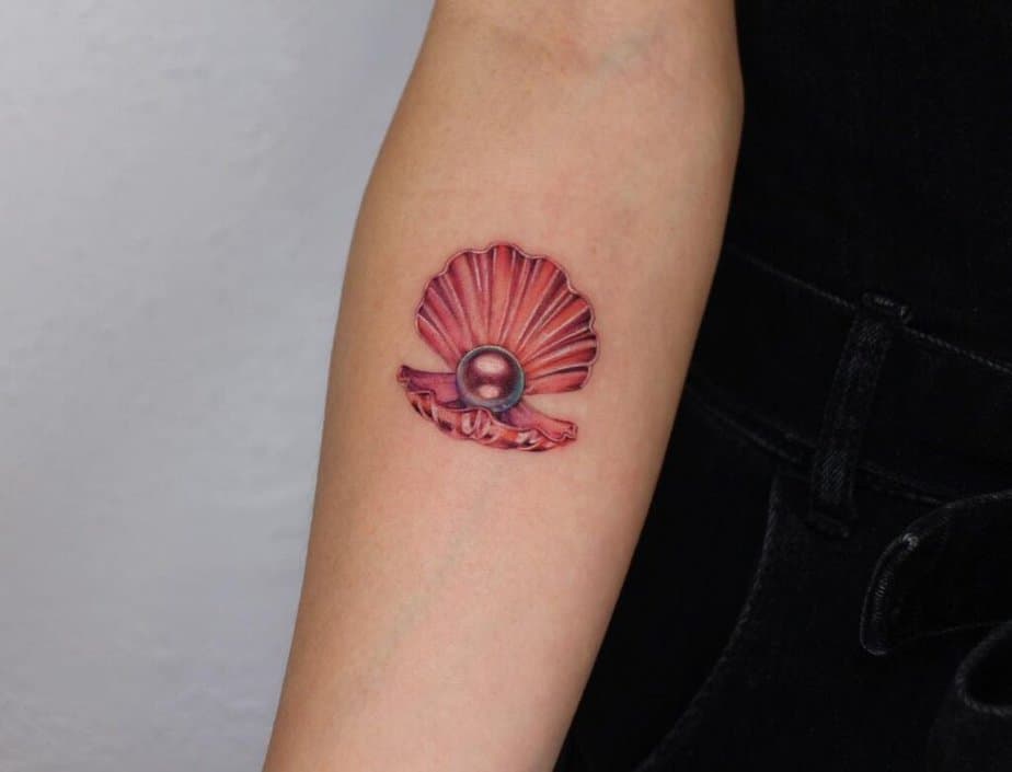8. A red seashell pearl tattoo on the forearm