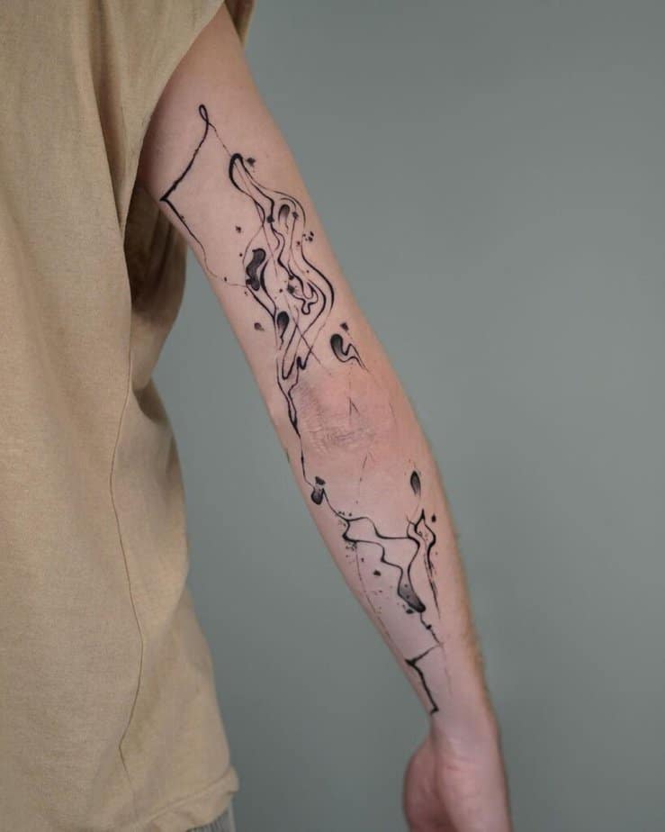 5. Un tatuaggio astratto in stile splatter sulla parte posteriore del braccio