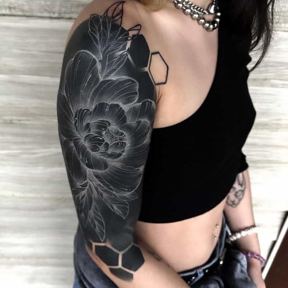 13. A black sleeve tattoo with flowers and geometric shapes 