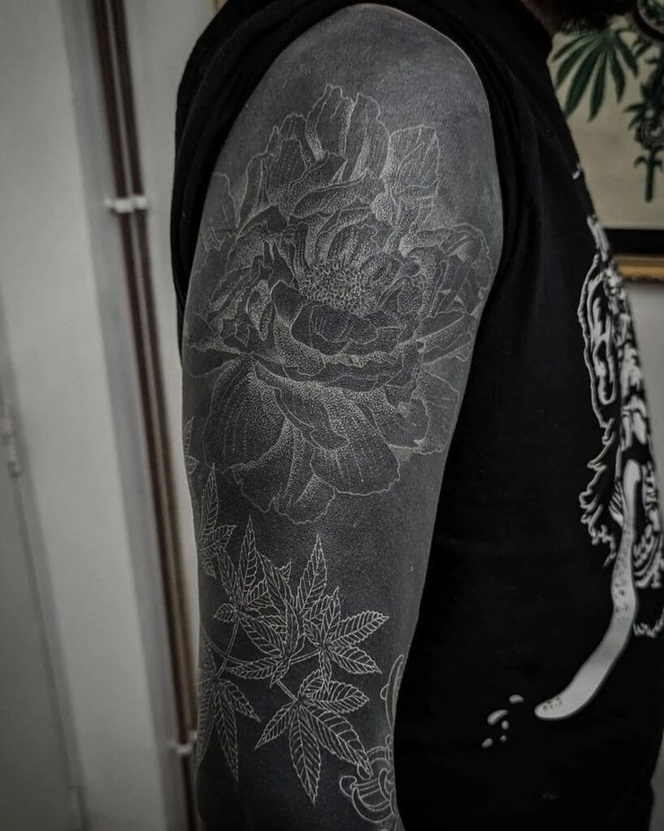 3. A black sleeve tattoo with a big white rose