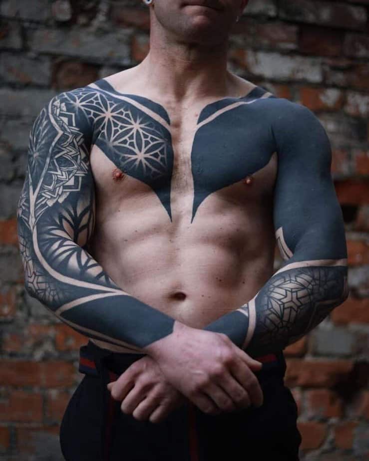 9. A black sleeve tattoo on both arms and chest