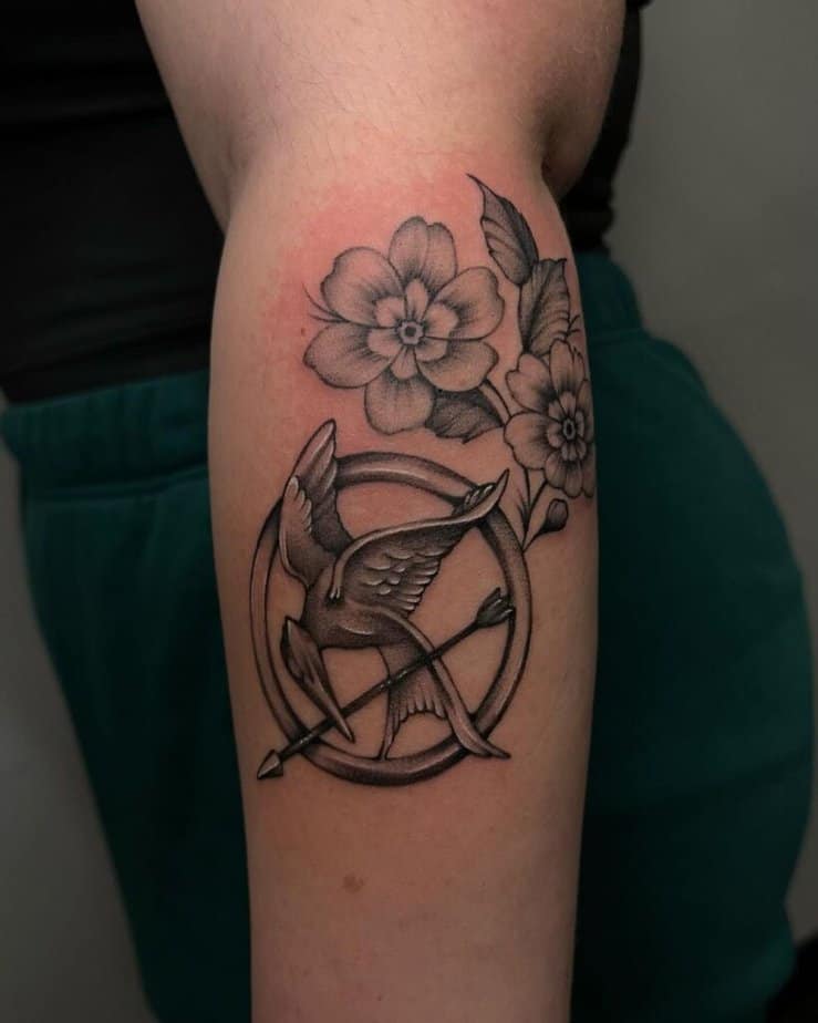 3. A tattoo of the Mockingjay symbol with primrose flowers