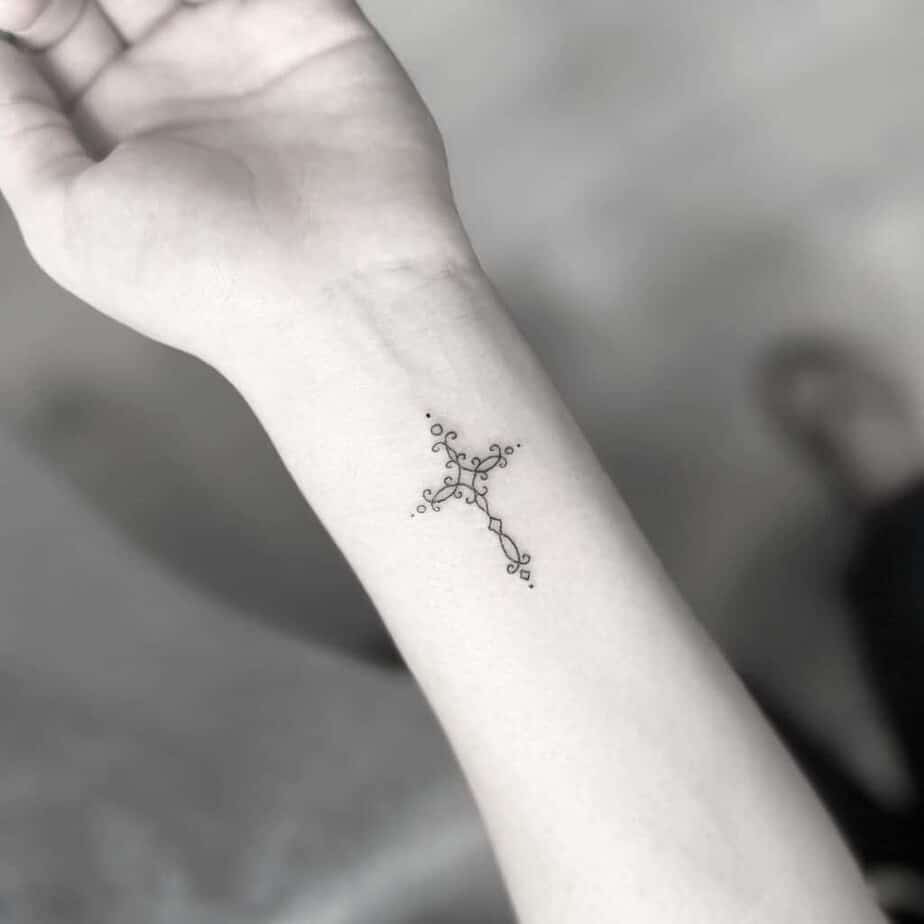 16. A minimalist vine cross tattoo