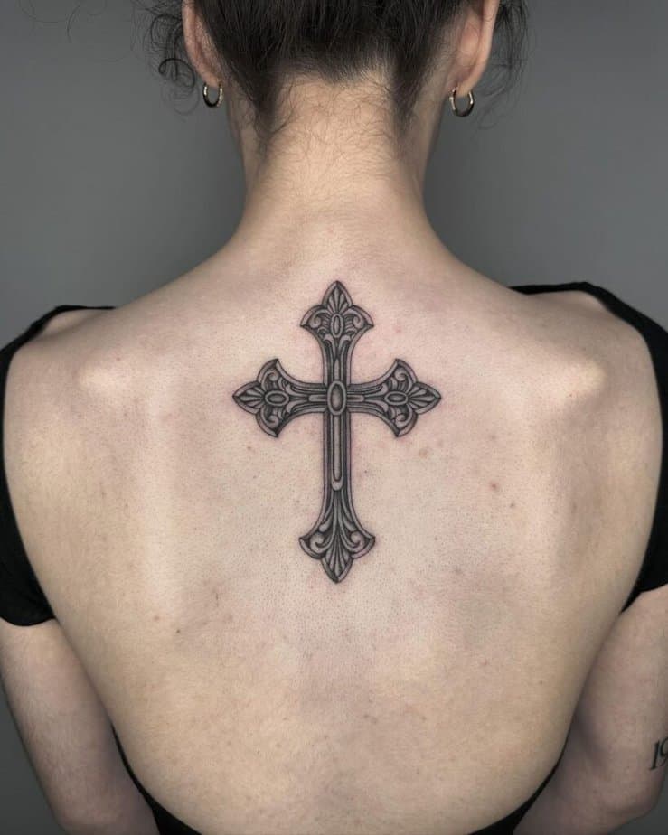 17. A gothic cross back tattoo for the stoic woman