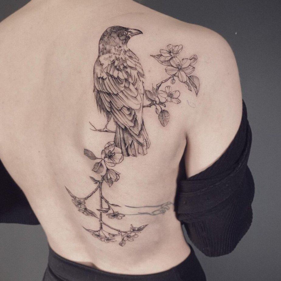 6. A back tattoo of a crow sitting on an apple tree 