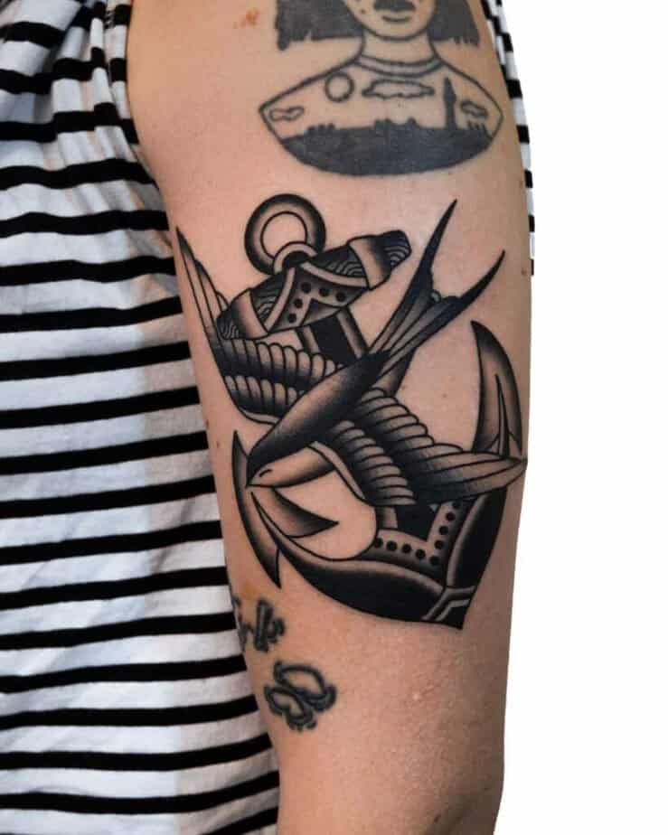 5. Impressionante tatuaggio sul braccio con un'ancora e una rondine