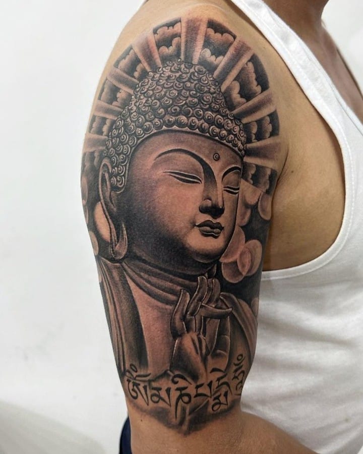 2. Un tatuaggio Buddha nero e grigio sulla parte superiore del braccio.