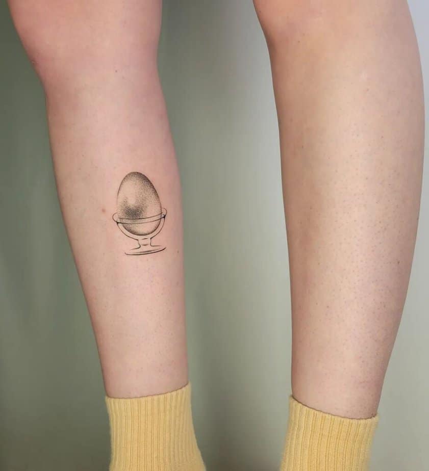 15. A dotwork tattoo of a realistic egg on the leg