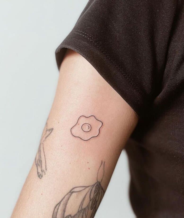7. A small and simple egg tattoo on the upper arm