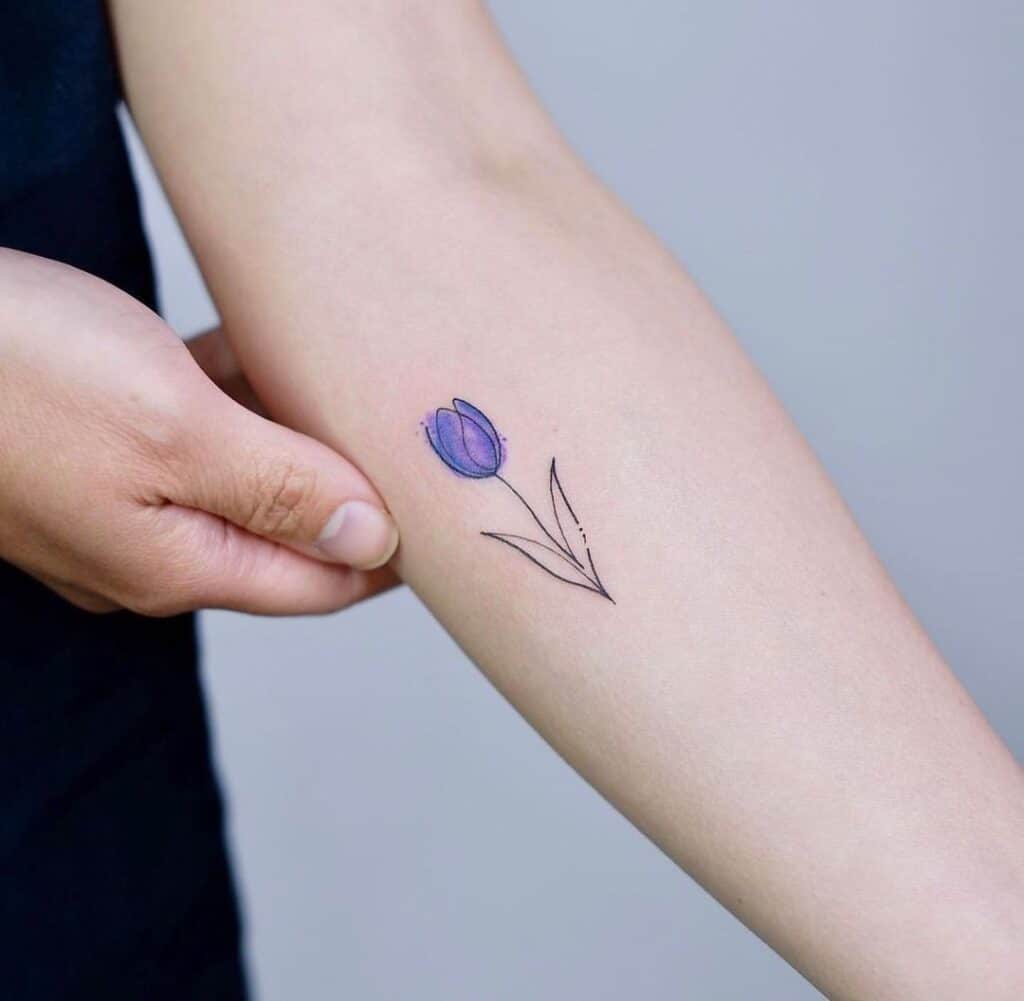 10. A linework tattoo of a purple tulip on the forearm
