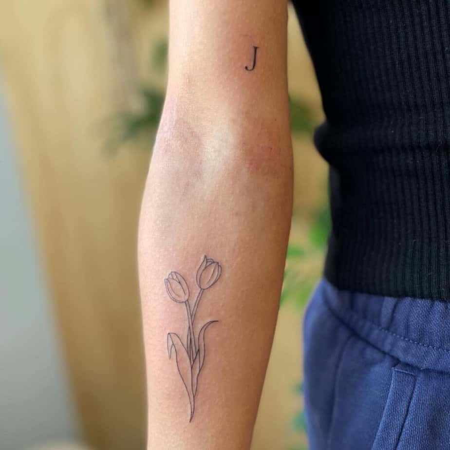 20. Un semplice e sottile tatuaggio a tulipano sull'avambraccio
