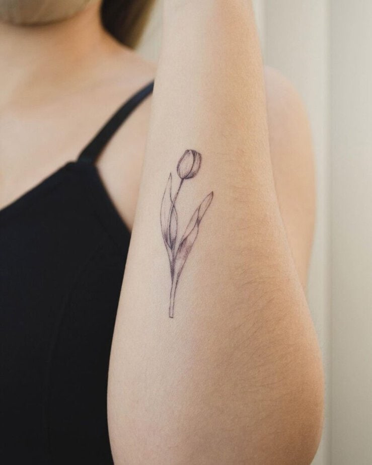 8. A fine-line tattoo of a tulip on the arm