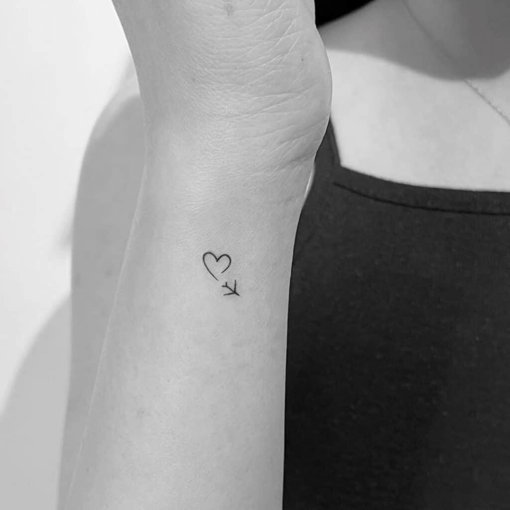 17. Tatuaggio a mano di un piccolo cuore con un aereo