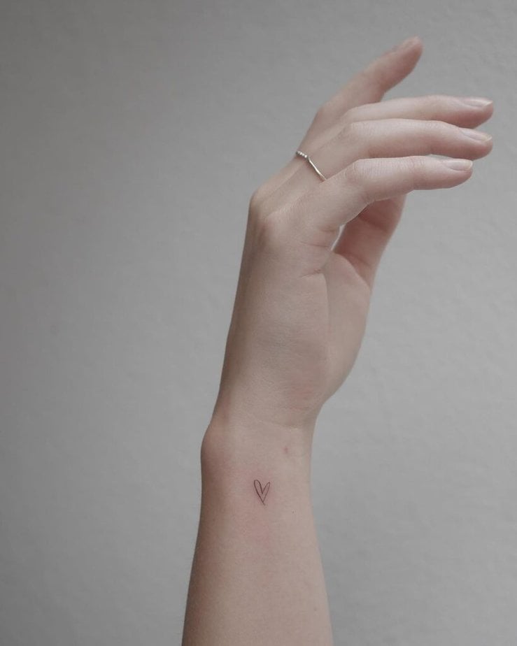 2. A delicate heart tattoo on the side of the wrist