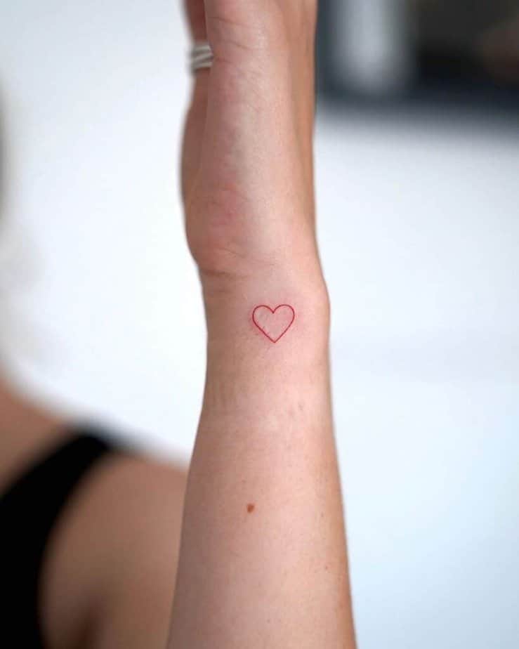 23. Tatuaggio a mano di un piccolo cuore con inchiostro rosso