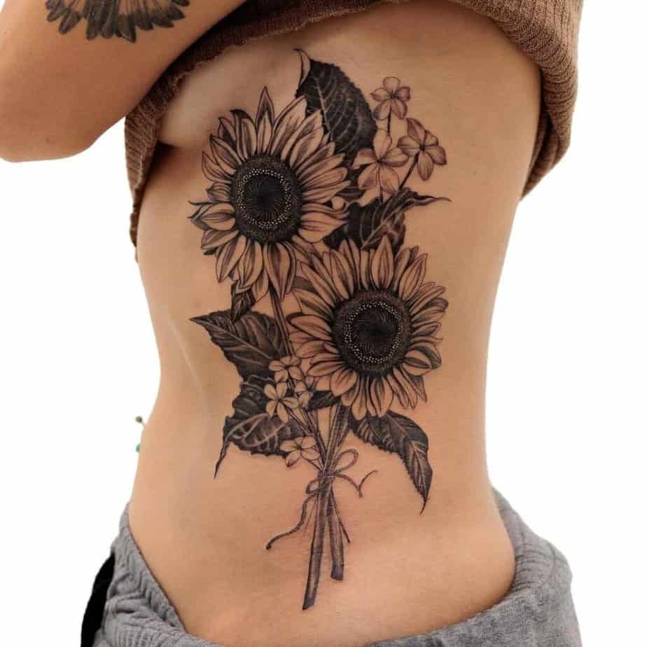 19. A statement sunflower tattoo on the side of the stomach