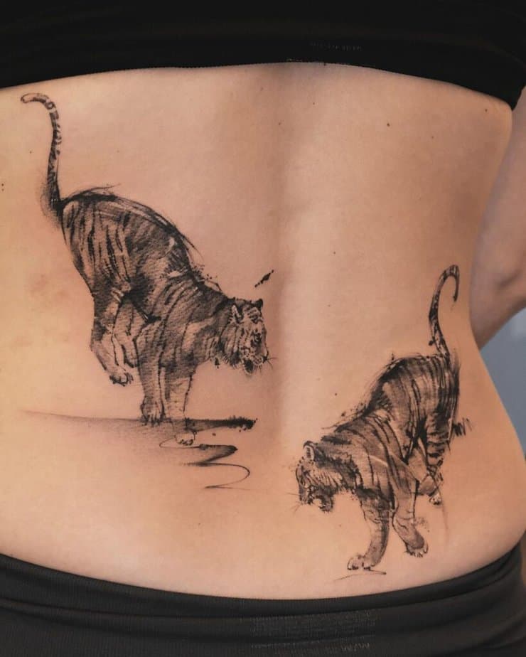 4. A back tattoo of two tigers playing with each other 
