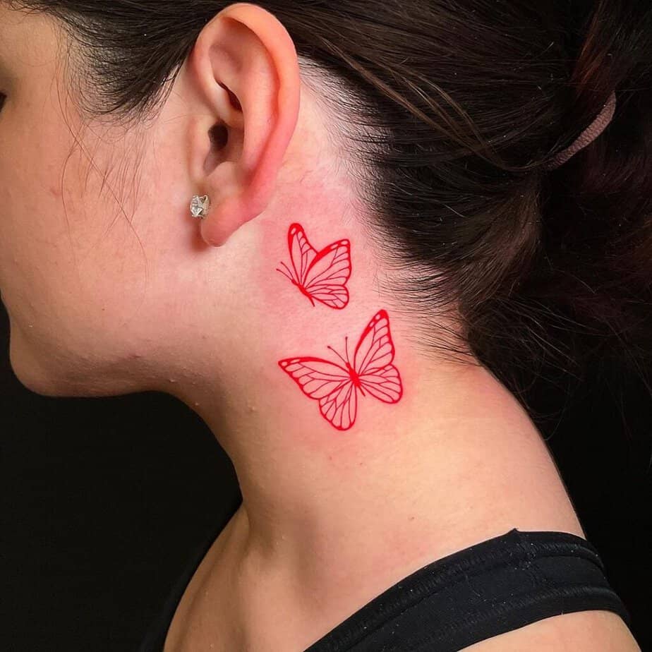 24. A red ink butterfly tattoo behind the ear 