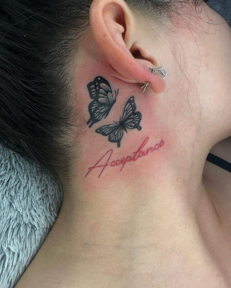 7. Tatuaggio di una farfalla dietro l'orecchio con un mantra 