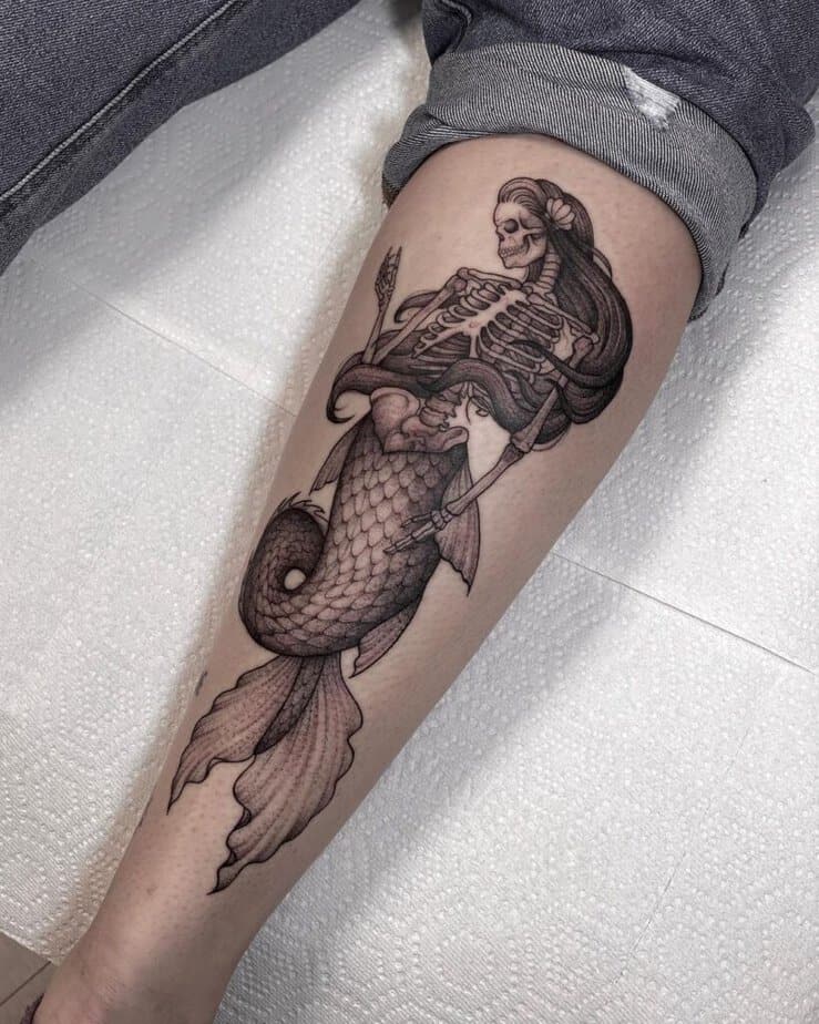 13. A skeleton mermaid tattoo on the leg