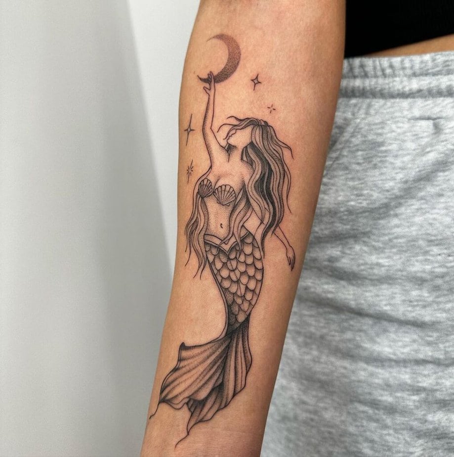 15. A tattoo of a mermaid reaching for the moon and stars 