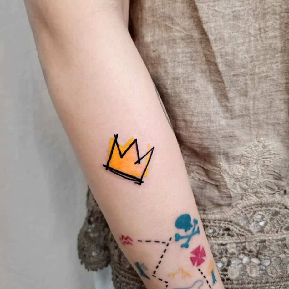 12. Tatuaggio di una corona di Basquiat sulla parte superiore del braccio