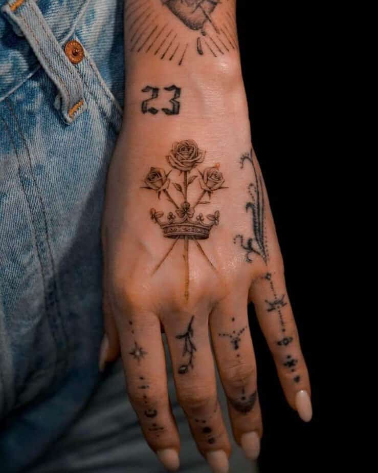 5. Tatuaggio di una corona con tre rose sulla mano 