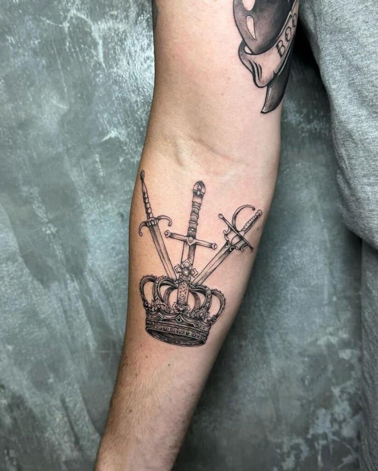 8. Tatuaggio di una corona con tre spade sull'avambraccio