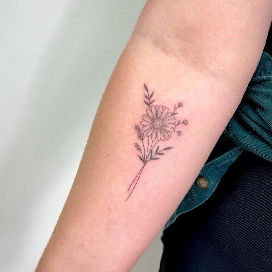 4. A tattoo of a daisy with some small wildflowers  