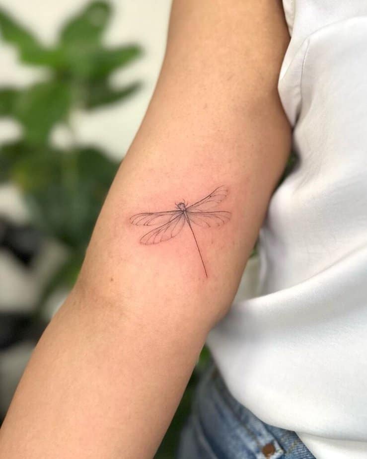 1. Un delicato tatuaggio a forma di libellula sul bicipite