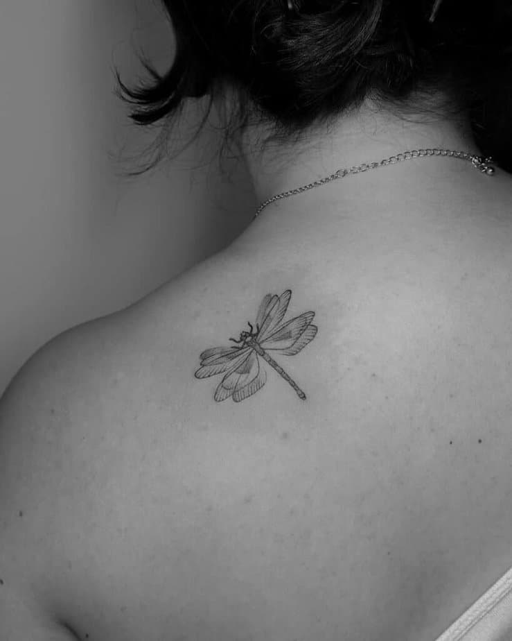14. Tatuaggio di una libellula svolazzante sul retro della spalla 