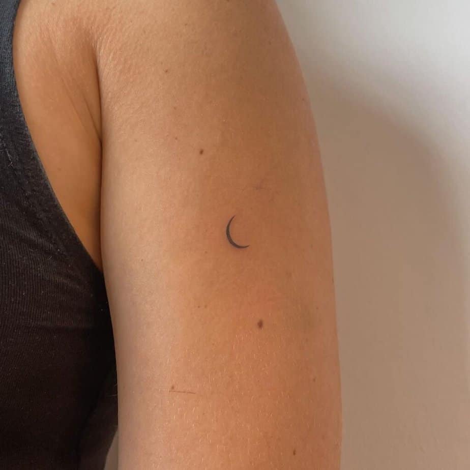4. Un delicato tatuaggio a forma di luna sulla parte superiore del braccio