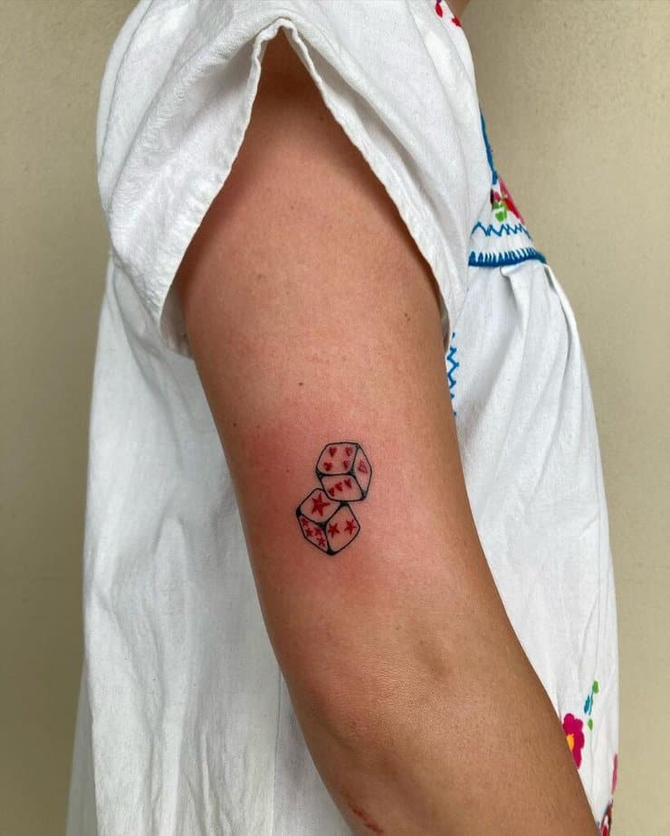 15. Tatuaggio con dadi neri e rossi sulla parte superiore del braccio